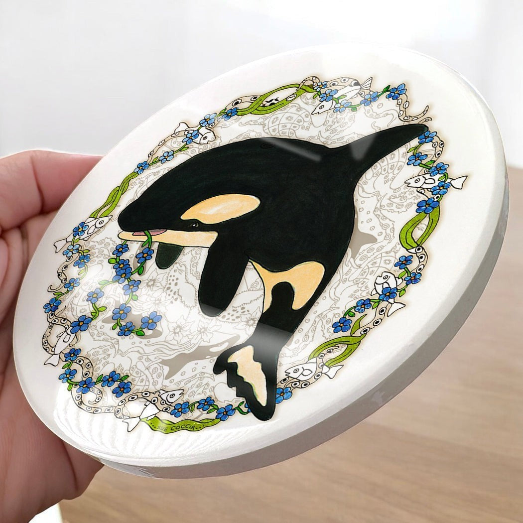 EarthArt International ceramic Orca whale coaster with floral and fish border. Black, white, yellow, blue, green.